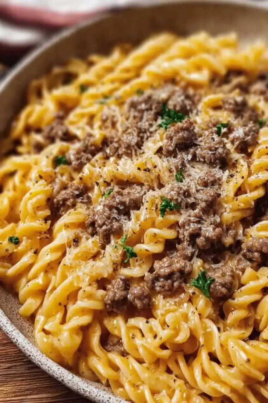 Creamy garlic butter beef pasta served in a bowl with herbs and cheese.