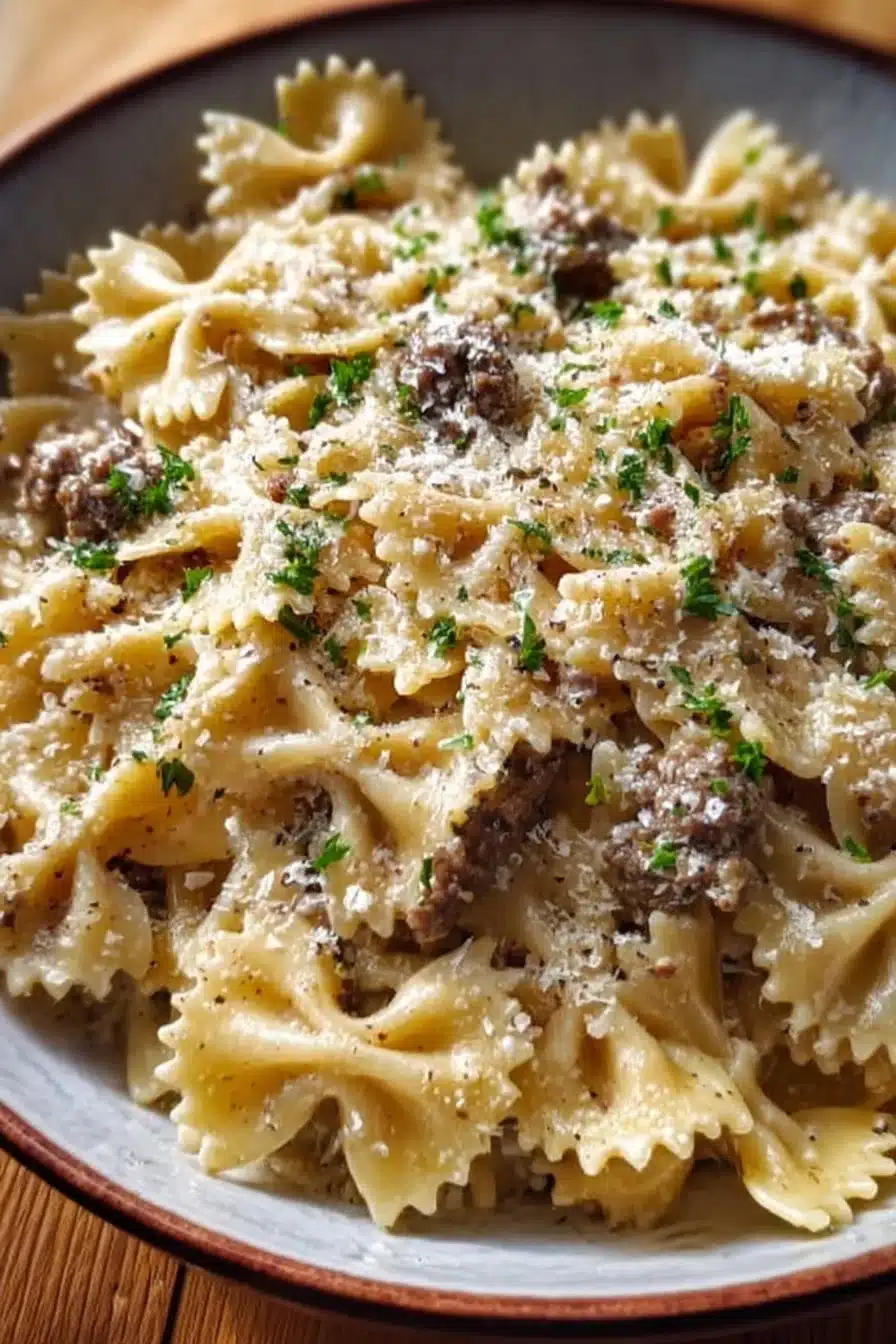 Creamy Parmesan beef pasta dish served in a bowl with herbs and cheese.